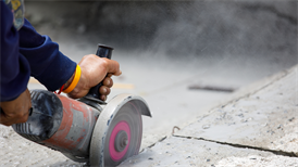 Cutting paving slab on construction site causing cloud of dust